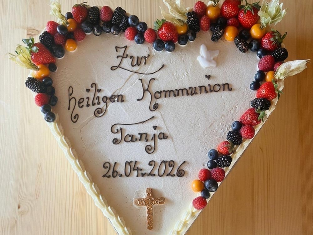 Herztorte: Weiße Torte mit Früchten und Schriftzug zur Kommunion von Tortenspezialist Niedermair